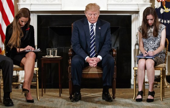 Image: President Donald Trump, joined by student Carson Abt, right, and Julia Cordover, the student body president at Marjory Stoneman Douglas High School  bow their heads during the opening prayer