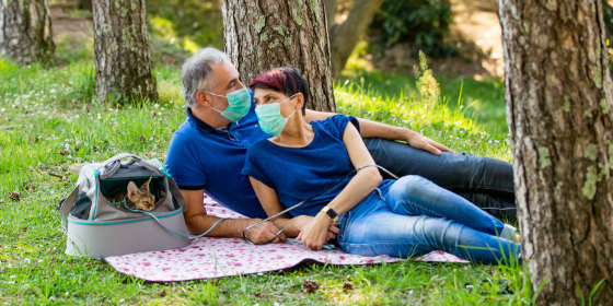Couple on picnic wearing face masks with their cat. Shop picnic essentials for a day in the park, backyard or roof, including a picnic basket, face mask, hand sanitizer, sunscreen and more.