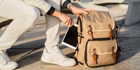 man pulling tablet out of backpack