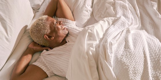 Woman relaxing in bed with her new sheets and mattress she gifted herself