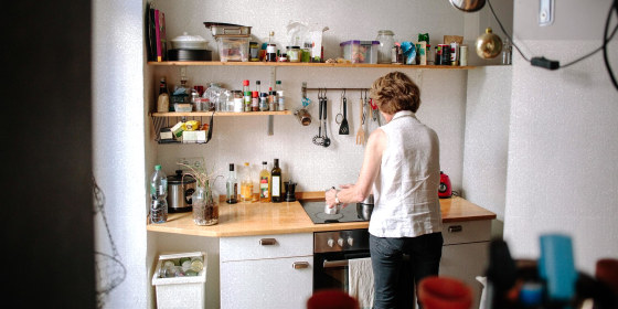 Rear view of senior woman making coffee on stove in kitchen at home