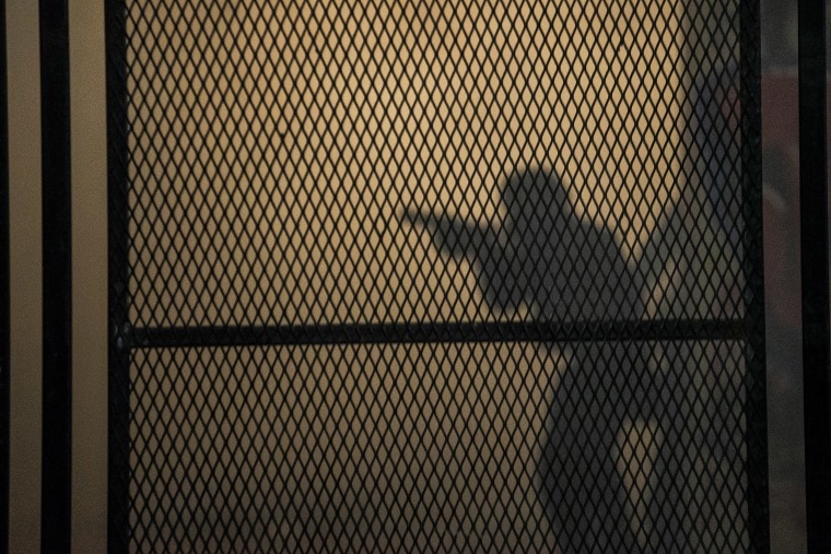 The outline of a federal officer behind a reinforced version of a fence