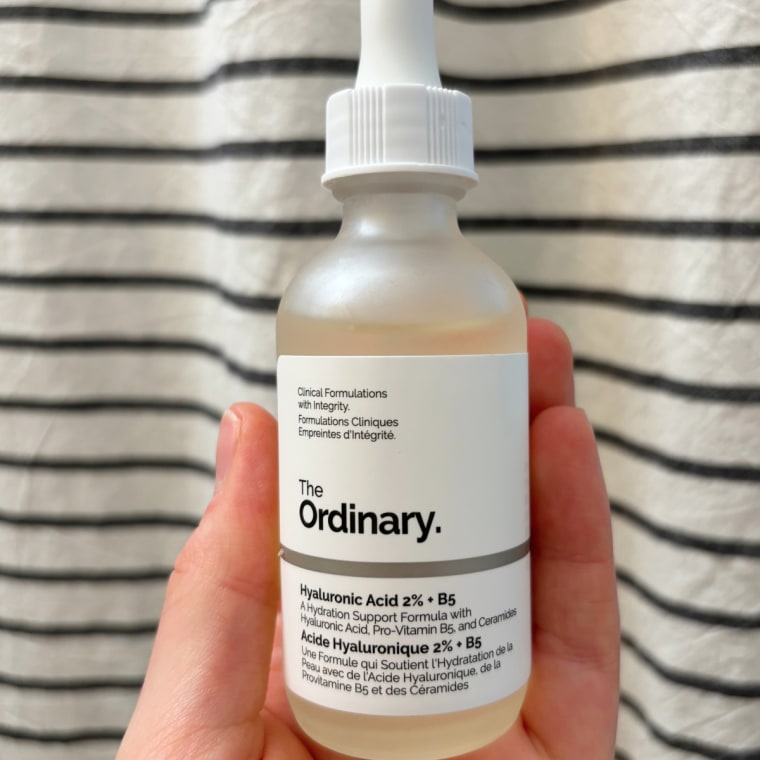 Woman holding serum bottle and taking out dropper
