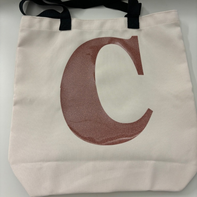 A monogrammed tote bag made with the Cricut Joy Xtra lays flat on a counter.