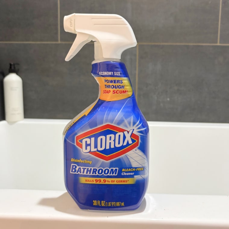 Spray bottle of Clorox disinfectant spray sitting on the side of the bathtub.