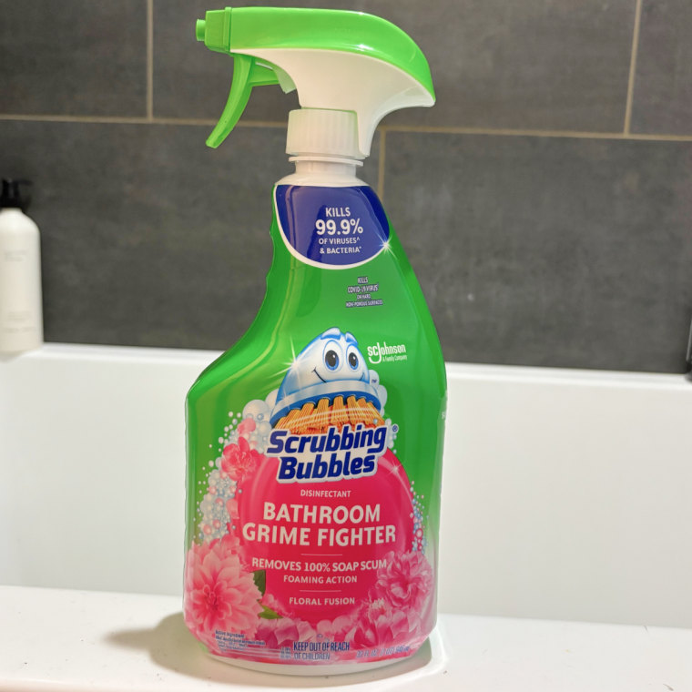 Scrubbing Bubbles shower cleaner spray sitting on the side of a bathtub.