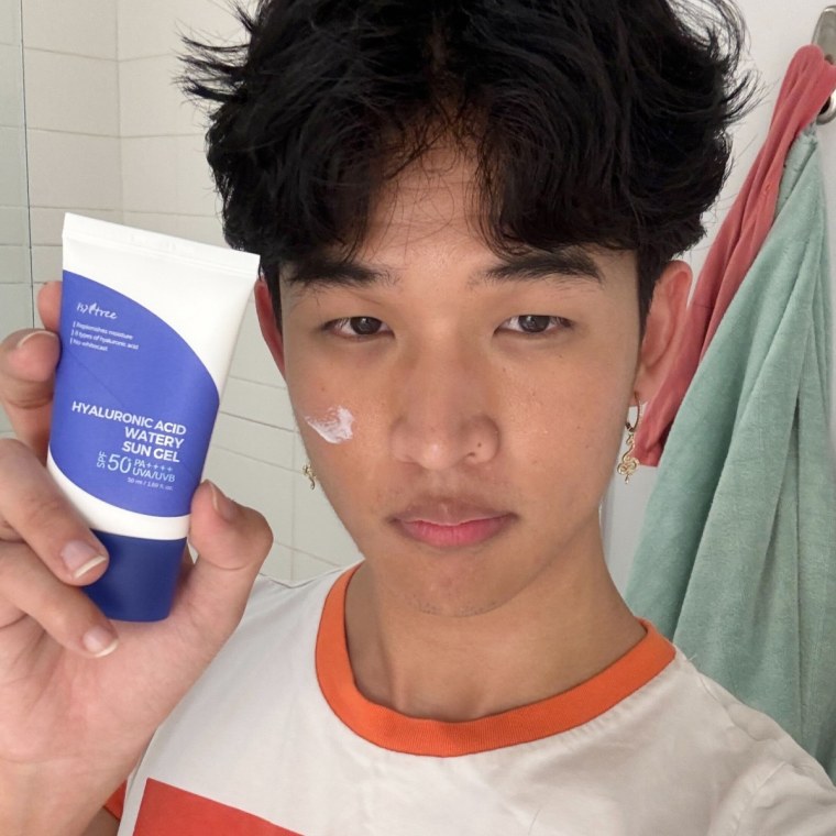 A man holds the sunscreen to his face with a swatch on his cheek.