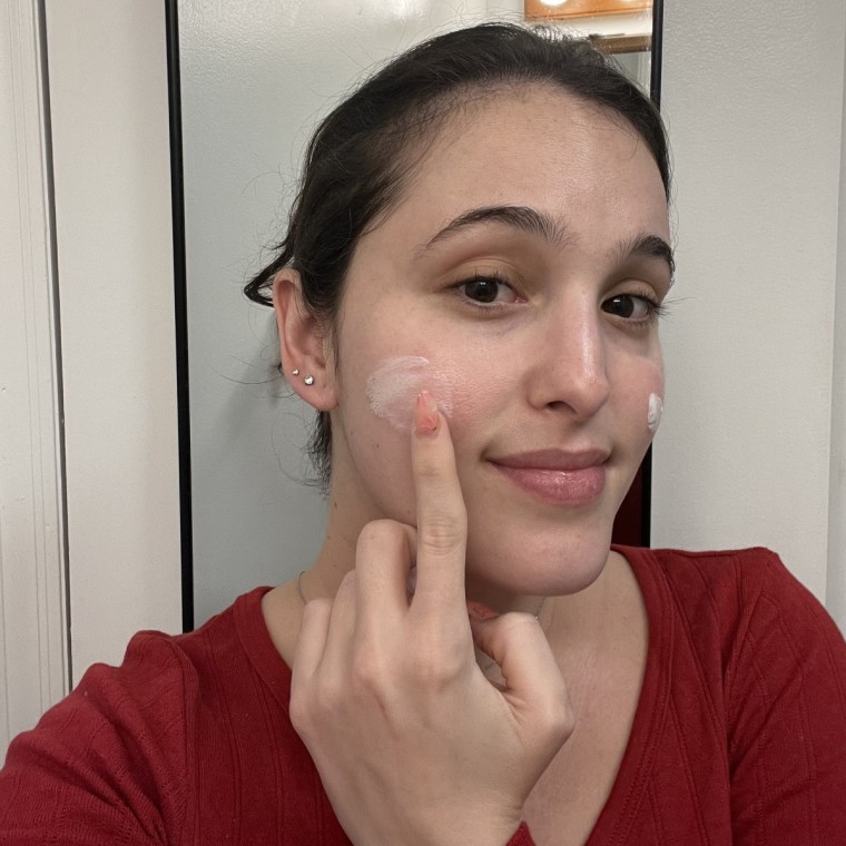Woman applying sunscreen to cheek.