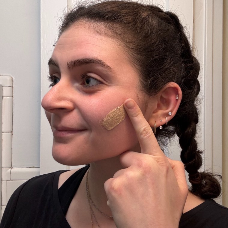 Woman swatches Naturium Dew-Glow Moisturizer on her cheek.
