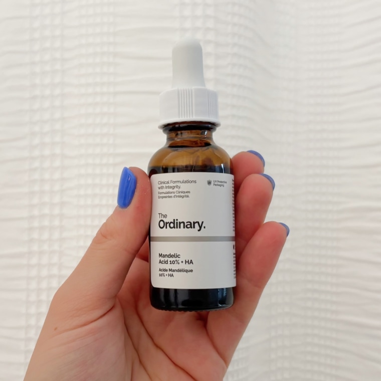 A bottle of The Ordinary’s Mandelic Acid 10% + HA serum against a white shower curtain.