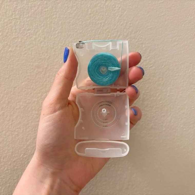 A Cocolab floss dispenser open to show the spool of blue floss inside.